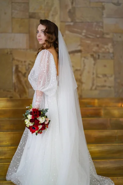 Retrato de uma noiva com cachos longos, em um vestido elegante na escada dourada — Fotografia de Stock