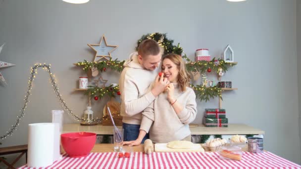 Mulher grávida com marido na cozinha de Ano Novo preparam a massa de farinha e comem bolos — Vídeo de Stock