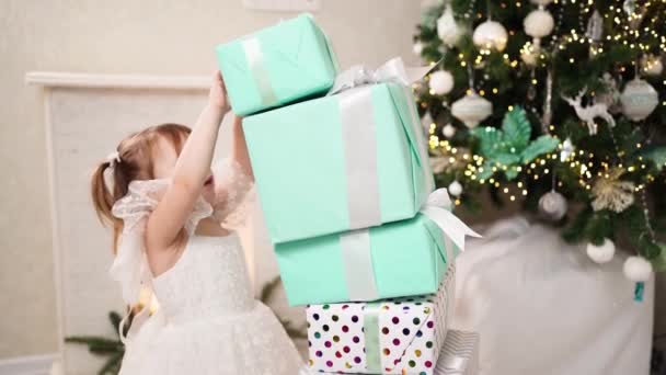 Bambina costruisce una torre di scatole regalo sotto l'albero di Natale e cade — Video Stock