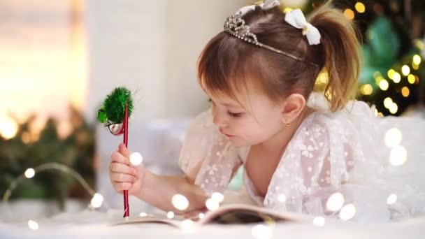 Mała dziewczynka pisze list do Świętego Mikołaja pod choinką. — Wideo stockowe