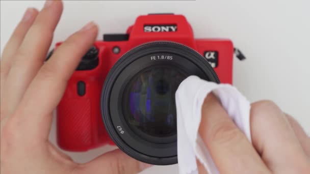 Служащий фотограф стирает объектив объектива камеры Sony. Профессиональное фотооборудование. — стоковое видео