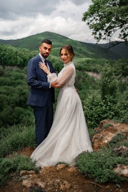 Dağlarda bir düğün töreninde yeni evlilere sarılan nazik, güzel bir kadın.