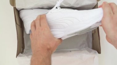 Adam kutudan yeni beyaz ayakkabılar çıkardı. Biçim, moda, imaj