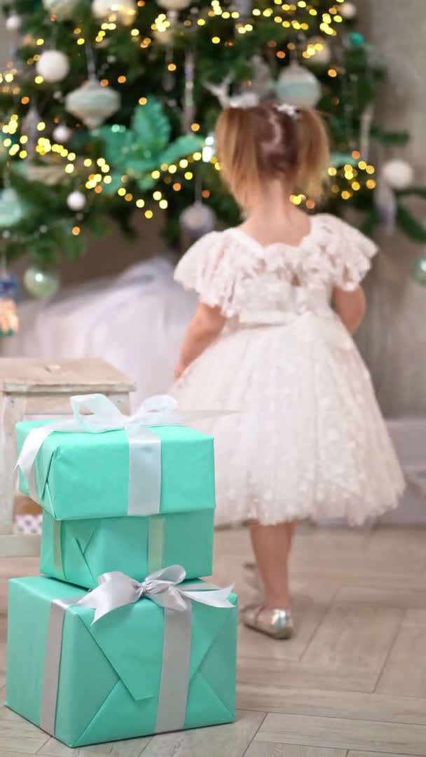 Küçük kız Noel ağacının altına hediye kutularından bir kule inşa eder ve düşer. — Stok video