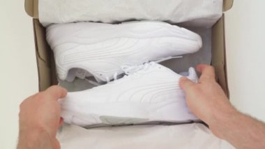 Adam kutudan yeni beyaz ayakkabılar çıkardı. Biçim, moda, imaj