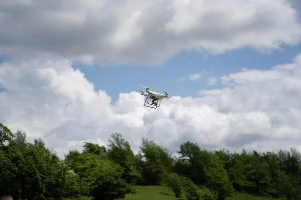 Un dron blanco vuela en el cielo azul sobre las montañas y dispara un video. — Foto de Stock