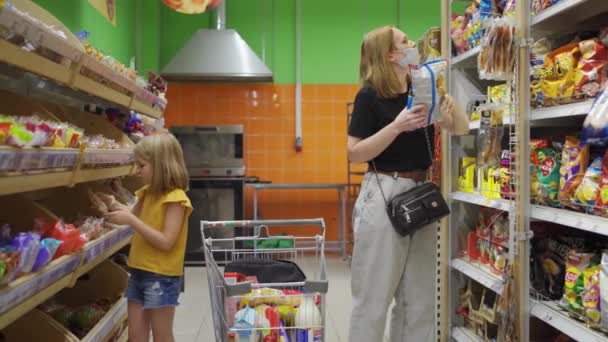 Bambina e giovane donna in maschera medica nel supermercato con carrello della spesa — Video Stock