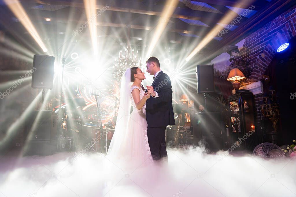the bride and groom dance on stage in the banquet hall of the restaurant. 
