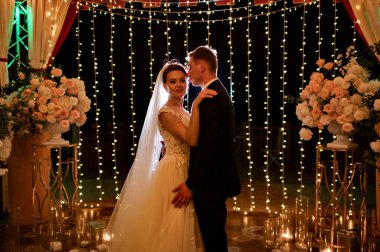 Akşam düğününde yeni evliler parkta ampullerin ve çelenklerin arasında..