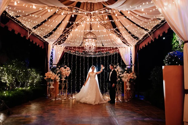De bruid en bruidegom op de nachtstraat tussen de bloemenslingers — Stockfoto