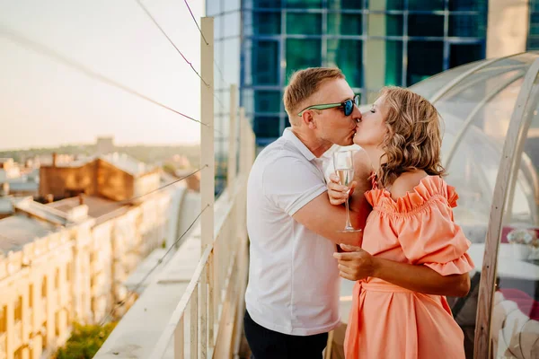 Homem e mulher bebem champanhe em bruderschaft em um café no telhado. — Fotografia de Stock