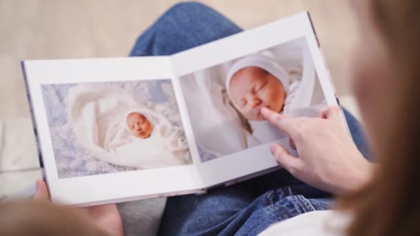 Στην κορυφή. μητέρα και κόρη παρακολουθήσουν photobook από την απαλλαγή του νεογέννητου μωρού — Αρχείο Βίντεο
