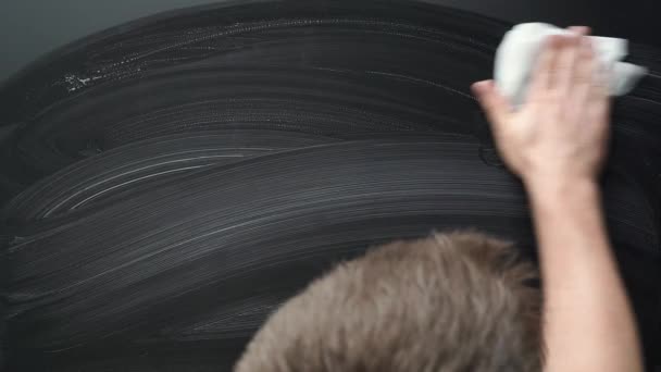De hand wast het zwarte oppervlak met een witte doek — Stockvideo