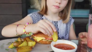 Komik küçük kız domates sosuna batırılmış fırında patates dilimleri yiyor Yaz Kafesi