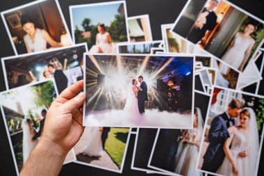 Eller düğün fotoğraflarını serer. Düğünde çalışan fotoğrafçıların sonuçları..