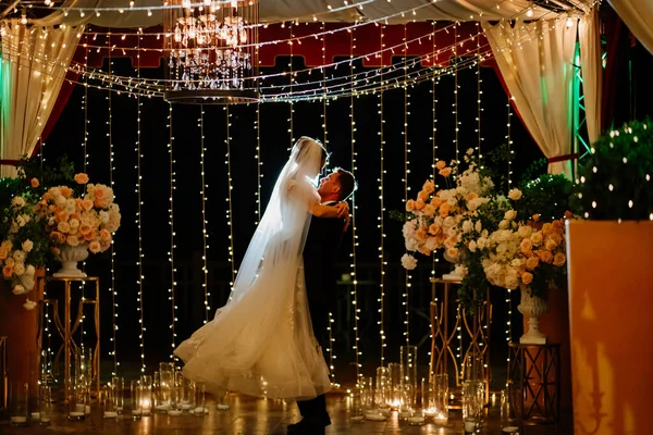 Nevěsta a ženich na noční ulici mezi věnci — Stock fotografie