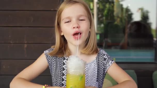 Zabawna dziewczynka pije tropikalny koktajl. kawiarnia rodzinna, weranda letnia — Wideo stockowe