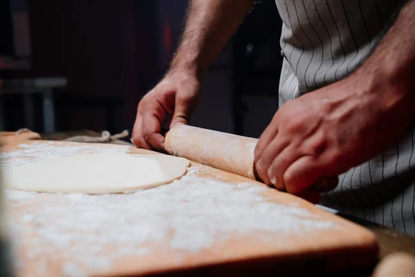 Руки розкачують тісто в тонкий шар. Готуємо піцу, локшину або піту в домашніх умовах — стокове фото