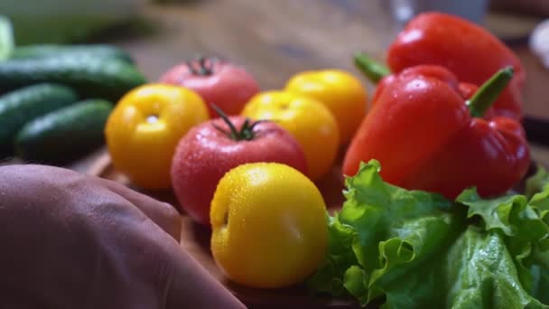 Разбрасывать помидоры, огурцы, салат и сладкий перец на деревянной круглой доске — стоковое видео