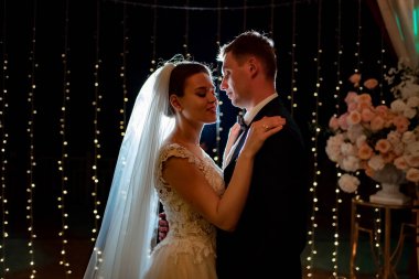 Gelin ve damat akşam düğününde parkta ampullerin arasında.