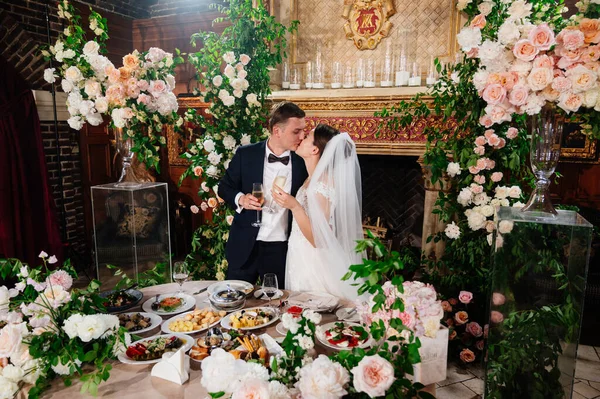 Šťastná nevěsta a ženich polibek v jídelně. slavnostní hostina. — Stock fotografie