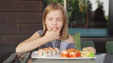 Kafe restoranında küçük bir kız Asya 'da Philadelphia usulü rulo yiyor.