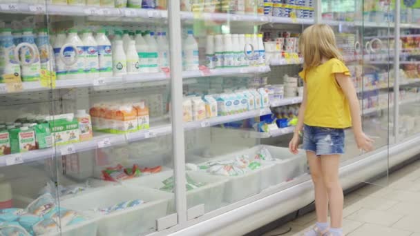 Divertida linda chica en el supermercado con carrito de compras elige qué comprar — Vídeo de stock