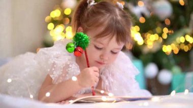 Küçük kız Noel ağacının altına Noel Baba 'ya mektup yazıyor..