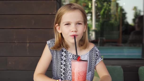 Vtipná holčička pije koktejlovou trubičkou jahodový koktejl. rodinná kavárna, letní veranda — Stock video