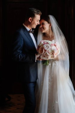 Karanlık bir iç mekanda buketi olan mutlu gelin ve damat.. 