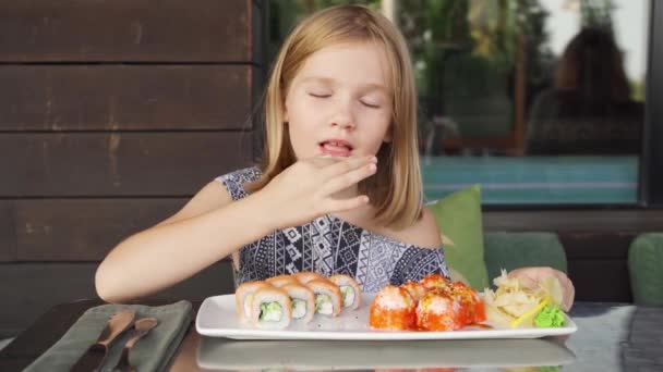 Klein meisje in cafe restaurant eet aziatische Philadelphia broodjes met veel plezier — Stockvideo