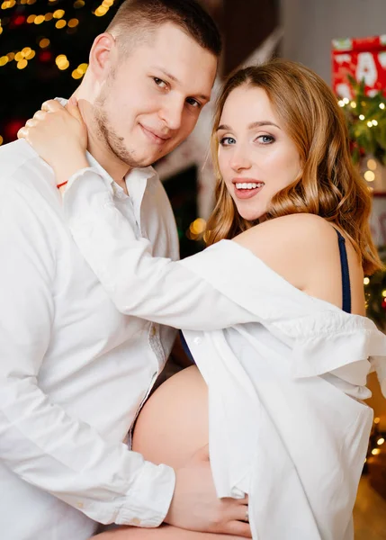 Una bella donna incinta e un uomo in camicie bianche nella cucina di Capodanno. — Foto Stock