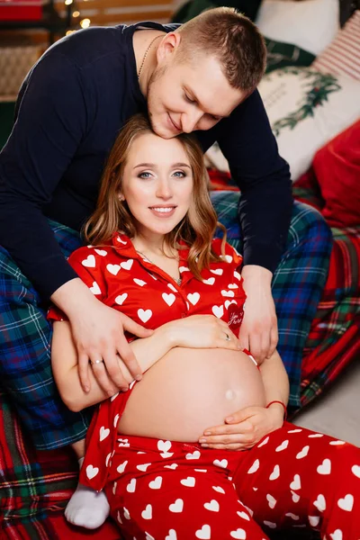 Uomo e donna innamorati. famiglia in pigiama nella camera da letto di Capodanno. gravidanza — Foto Stock