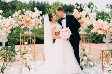 Gelin ve damat, canlı beyaz ve pembe çiçeklerin düğün alanında.. 