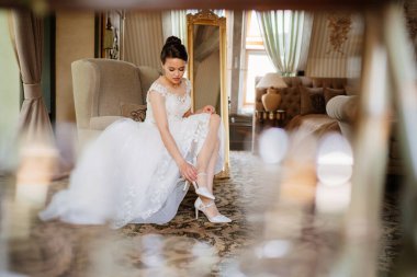 Beyaz elbiseli güzel bir gelin ayakkabılarını giyer. düğün modası. 