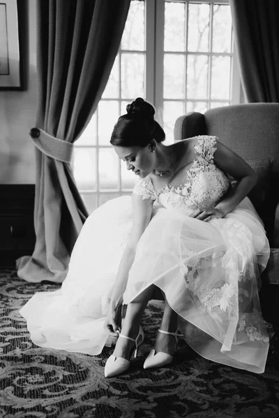 Una hermosa novia en un vestido blanco se pone los zapatos. moda de boda. — Foto de Stock