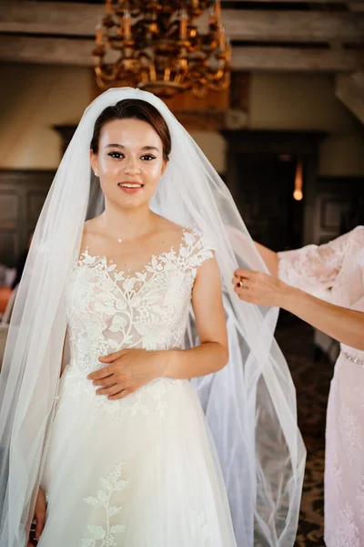 A noiva ajuda-se a pôr um vestido e véu — Fotografia de Stock