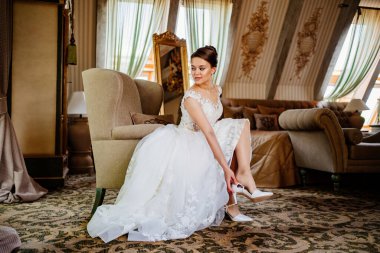 Beyaz elbiseli güzel bir gelin ayakkabılarını giyer. düğün modası. 