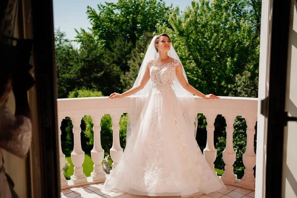 Gelin beyaz dantelli bir elbise ve terasta uzun bir peçe duruyor.. — Stok fotoğraf