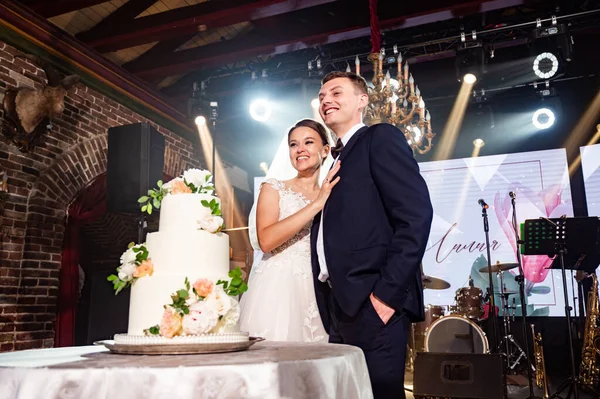 Braut und Bräutigam mit traditioneller weißer Hochzeitstorte, geschmückt mit Blumen — Stockfoto