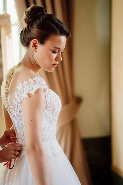 Der Braut wird geholfen, ein Kleid anzuziehen und das Korsett zu befestigen. — Stockfoto