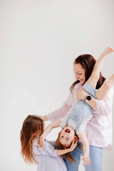 Hermosa familia feliz en un estudio de fotos en blanco. Mamá y dos hijas — Foto de Stock