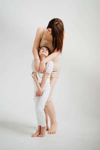 Mamá y su hija posan en un estudio de fotografía en blanco. — Foto de Stock