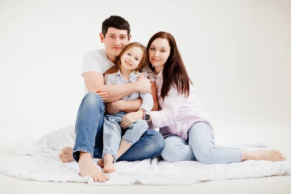Belle famille heureuse câlinant dans un studio photo blanc. dans les coulisses. — Photo