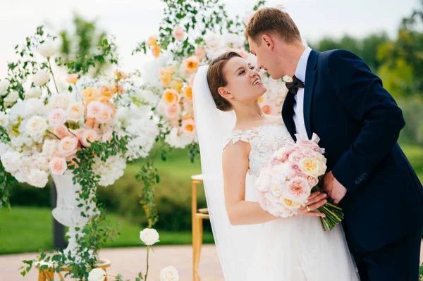 Braut und Bräutigam im Bereich der Hochzeitszeremonie aus lebenden weißen und rosa Blumen. — Stockfoto