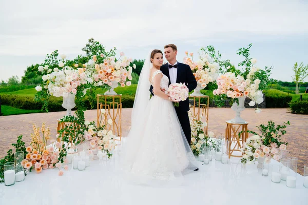 Nevěsta a ženich v oblasti svatební obřad živých bílých a růžových květin. — Stock fotografie