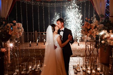 Gelin ve damat gece sokağında çelenklerin arasında