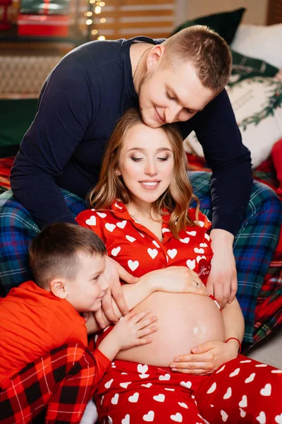 Hermosa familia feliz en pijama en el dormitorio de Año Nuevo. embarazo — Foto de Stock