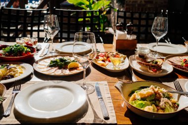 Salata, abur cubur, çatal bıçak ve bardaklarla servis edilen ahşap masa.. 