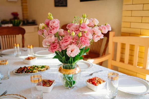 Ramo de flores de color rosa en un jarrón sobre la mesa servido en la terraza. — Foto de Stock